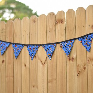 May include: A blue and black bunting with a Mickey Mouse pattern hangs on a wooden fence.