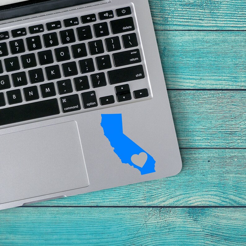 May include: A blue outline of the state of California with a white heart in the center, on a silver laptop.