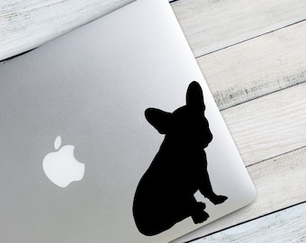 May include: A black silhouette of a French Bulldog sitting on a silver laptop.