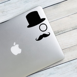 May include: A black and white sticker of a top hat, monocle, and mustache on a silver laptop.