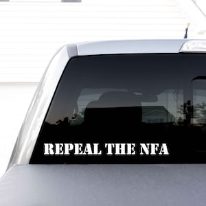 May include: A white vinyl sticker on the back window of a silver truck that reads "Repeal the NFA".
