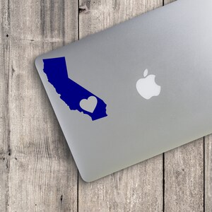 May include: A blue outline of the state of California with a white heart in the center, on a silver laptop.