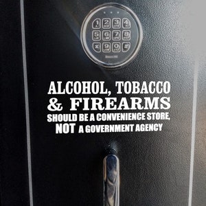 May include: A black safe with a combination lock and a white sticker that reads "ALCOHOL, TOBACCO & FIREARMS SHOULD BE A CONVENIENCE STORE, NOT A GOVERNMENT AGENCY."