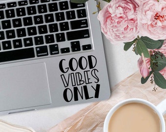 May include: A silver laptop computer with a black keyboard and a black sticker that says "GOOD VIBES ONLY" on the top right corner of the laptop.