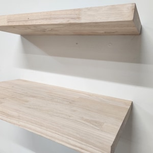 Puede incluir: Dos estantes flotantes rectangulares hechos de madera natural de color claro con un patr&oacute;n de veta visible. Los estantes est&aacute;n montados horizontalmente, uno encima del otro, con superficies lisas y bordes rectos y limpios.