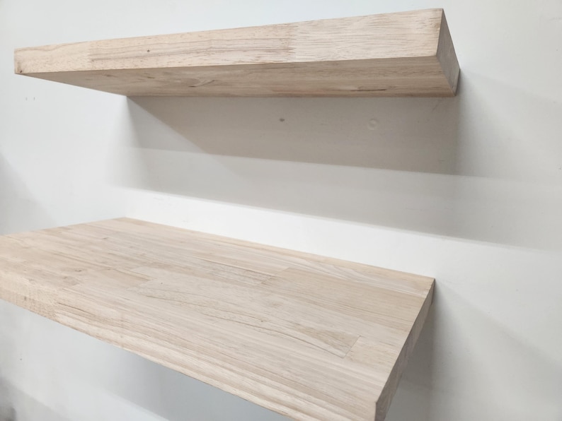 Puede incluir: Dos estantes flotantes rectangulares hechos de madera natural de color claro con un patr&oacute;n de veta visible. Los estantes est&aacute;n montados horizontalmente, uno encima del otro, con superficies lisas y bordes rectos y limpios.