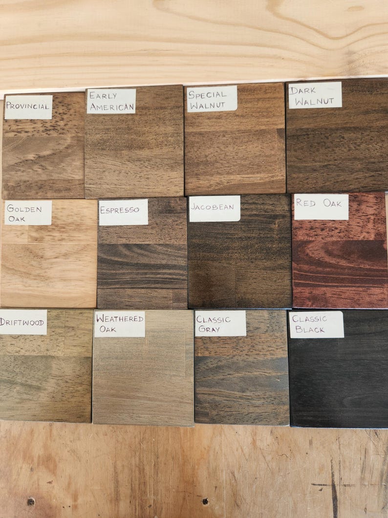 Puede incluir: Una colecci&oacute;n de doce muestras cuadradas de tinte para madera dispuestas en una cuadr&iacute;cula. Cada muestra presenta un patr&oacute;n de veta y color distintos, etiquetadas con etiquetas de papel blanco que dicen Provincial, Early American, Special Walnut, Dark Walnut, Golden Oak, Espresso, Jacobean, Red Oak, Driftwood, Weathered Oak, Classic Gray y Classic Black.