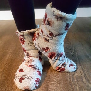 May include: Cozy gray slipper boots with a floral pattern in shades of red and brown. The boots have a soft, fluffy lining and are designed to keep feet warm. The boots are made of a soft, comfortable material.