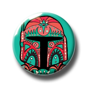 May include: A colourful button featuring a stylised illustration of a Boba Fett helmet with intricate patterns in shades of red, green and black.