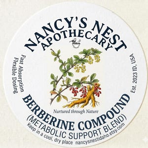 May include: A circular white label for Nancy's Nest Apothecary featuring a botanical illustration of a barberry plant with yellow flowers, red berries, and roots. Text includes Berberine Compound, Metabolic Support Blend, and Nurtured through Nature.