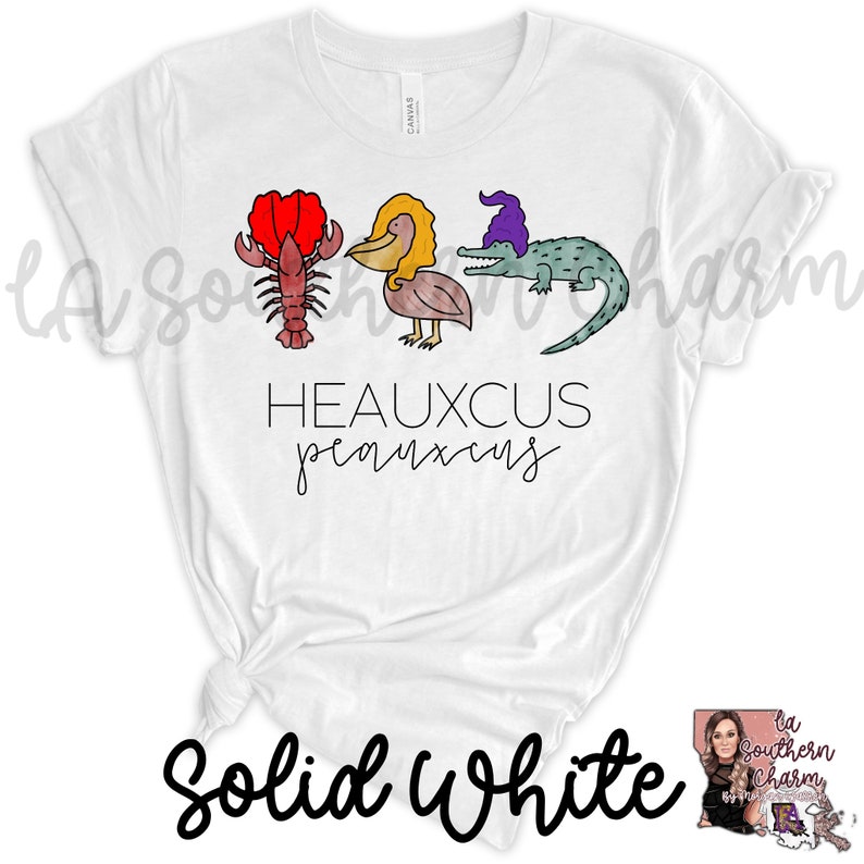 May include: White t-shirt with a graphic of a lobster, pelican, and alligator with the text "Heauxcus  peanuts" printed on it.