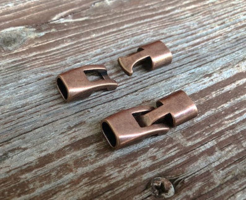 Peut inclure: Deux fermoirs en m&eacute;tal de couleur cuivre antique pour la fabrication de bijoux. Les fermoirs sont con&ccedil;us pour &ecirc;tre utilis&eacute;s avec des cordons en cuir ou en tissu.