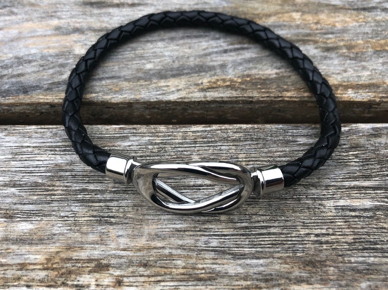 May include: A black leather bracelet with a silver knot clasp.