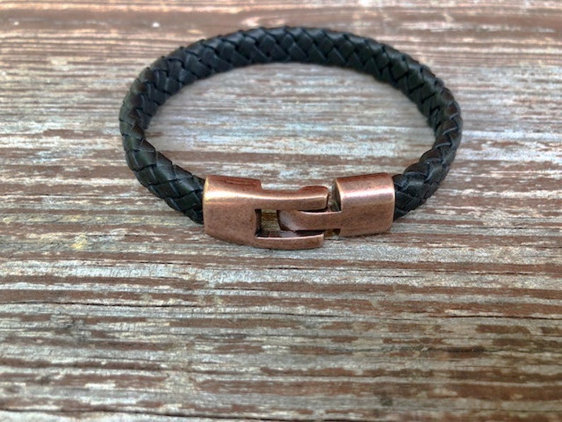 Peut inclure: Un bracelet en cuir tress&eacute; noir avec une fermeture en cuivre.