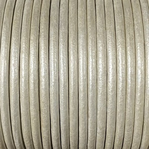 May include: A close-up of a spool of off-white leather cord. The cord is smooth and has a slight sheen.