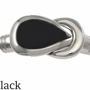 May include: A silver tie clip with a black oval inlay. The tie clip is shaped like a knot.