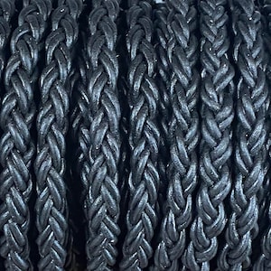 May include: Close-up of black braided leather cord. The cord is tightly woven and has a smooth, polished finish.