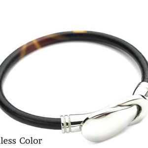 May include: A black leather bracelet with a silver clasp. The leather has a tortoiseshell pattern.