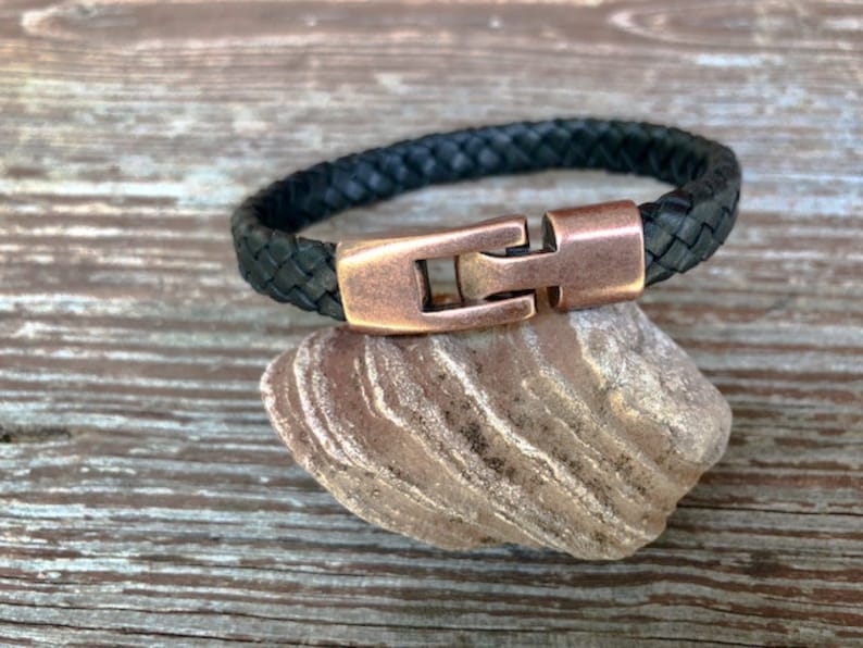 Peut inclure: Un bracelet en cuir tress&eacute; noir avec une fermeture en cuivre.