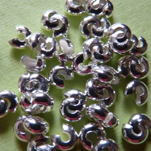 May include: A pile of silver-toned metal crimp beads, used for jewelry making.
