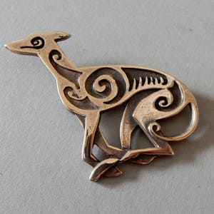 Running greyhound, in profile, facing right, with legs crossed under body.  Body is decorated with cut in Celtic spirals.  Bronze by Master Ark.