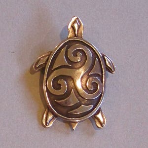 Peut inclure: Un pendentif en bronze en forme de tortue avec un motif de nœud celtique. La tortue est détaillée avec une carapace texturée et quatre pattes.
