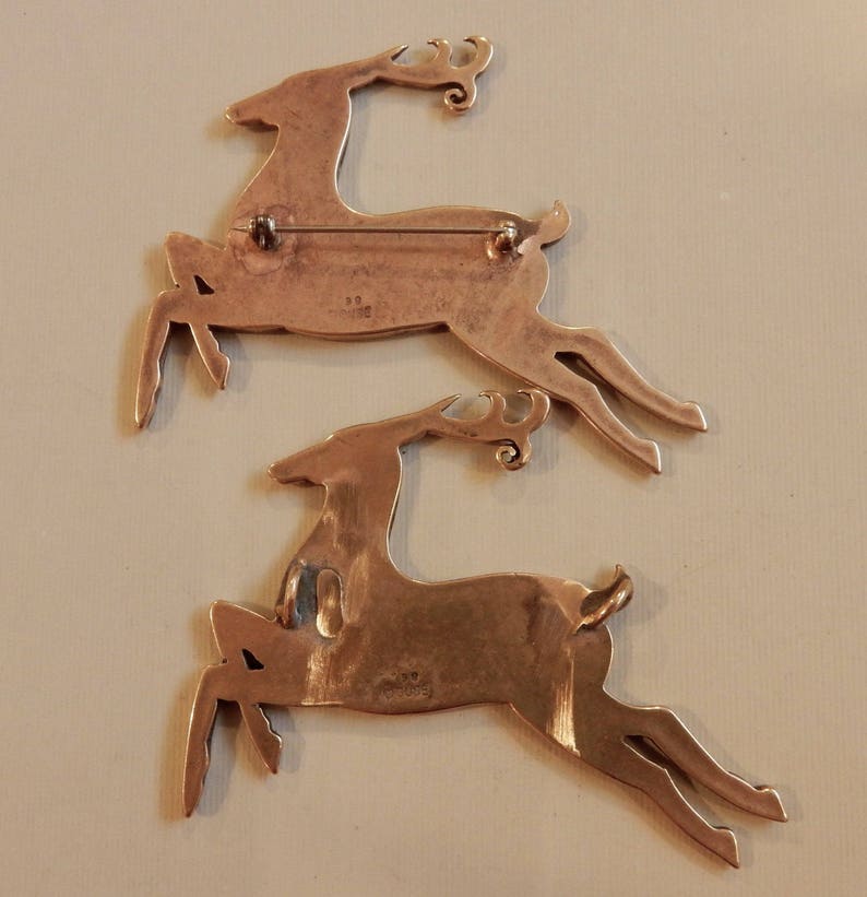 Backs of two leaping stags, one with a pin back, one with two cast suspension loops.  Stamped with Copyright Guse 98.