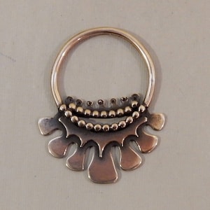 Op de afbeelding: Een gouden oorring met een decoratief, gegolfd ontwerp. De oorring heeft een rij kleine kralen rond de bovenkant van de hoepel.