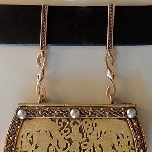 Two bronze bars on a belt with S hooks attached to the suspension loops at the bottom. A belt purse is hanging from the S hooks.  By Master Ark.