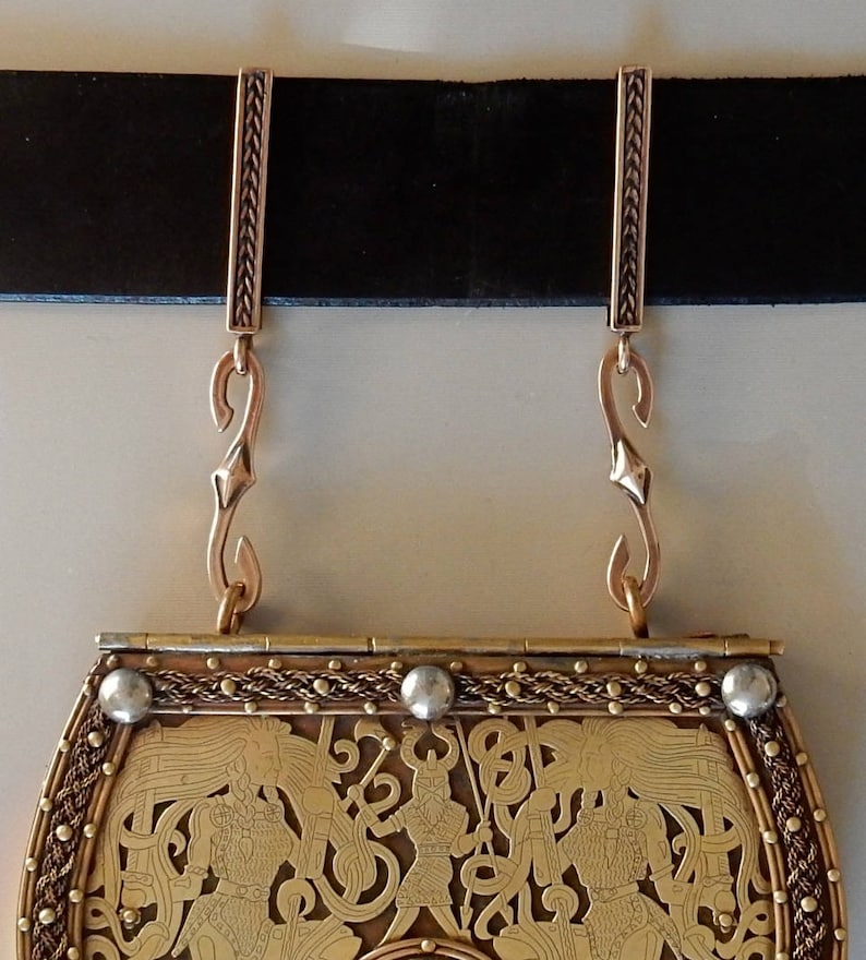Two bronze bars on a belt with S hooks attached to the suspension loops at the bottom. A belt purse is hanging from the S hooks.  By Master Ark.