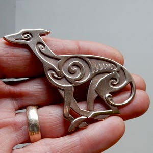 Running greyhound, in profile, facing right, with legs crossed under body.  Body is decorated with cut in Celtic spirals.  Bronze by Master Ark.