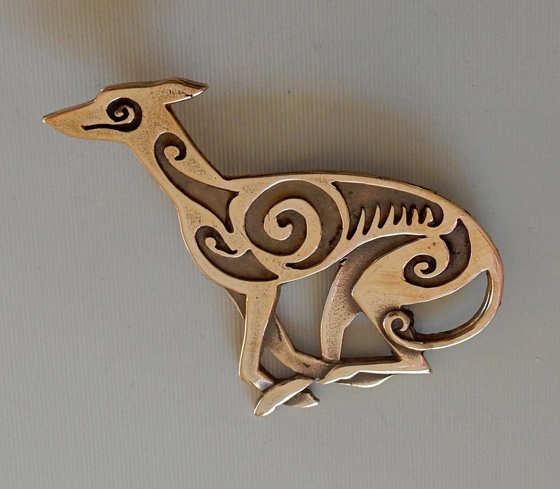 Running greyhound, in profile, facing right, with legs crossed under body.  Body is decorated with cut in Celtic spirals.  Bronze by Master Ark.