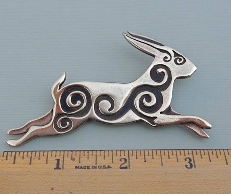 Running rabbit in profile, facing right.  Decorated with Celtic spirals cut into the body.  Pictured with ruler - 3 1/4 inches long. 
 Bronze by Master Ark.