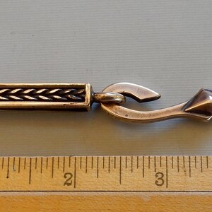 A bronze bar with an S hook attached to the suspension loop at the bottom. Shown with a ruler - 4 1/2 inches total length of loop and hook.  By Master Ark.
