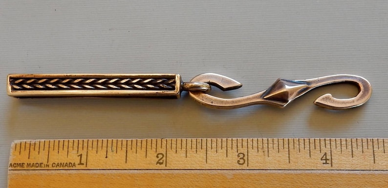A bronze bar with an S hook attached to the suspension loop at the bottom. Shown with a ruler - 4 1/2 inches total length of loop and hook.  By Master Ark.