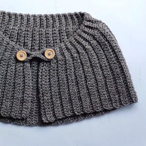 May include: A grey crocheted cowl with two wooden buttons.