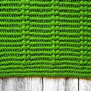 May include: A green crocheted rug with a textured pattern. The rug is made with a thick yarn and has a soft, fuzzy texture.
