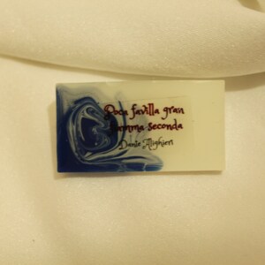 May include: A white rectangular soap bar with blue marbling. The soap has the text "Poca favilla gran fiamma seconda" and "Dante Alighieri" printed on it.