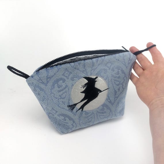 Kleine Kulturtasche mit Silhouette Hexe auf dem Besen vor