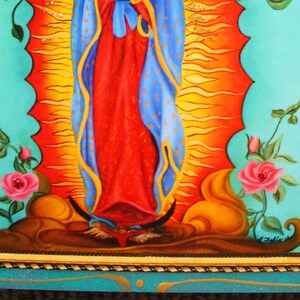 May include: A framed religious painting featuring a central figure in red and blue robes, set against a radiant orange and yellow background. The artwork is bordered by a turquoise frame with floral accents and pink roses.
