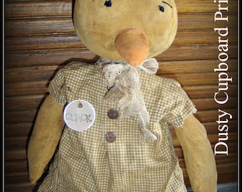 May include: A brown and white gingham dress with a brown felt head and a brown felt beak. The doll has a brown felt body and a white felt scarf. The doll is labeled "Miss Quackers" and "Dusty Cupboard Prims" and has a tag that says "Quack".