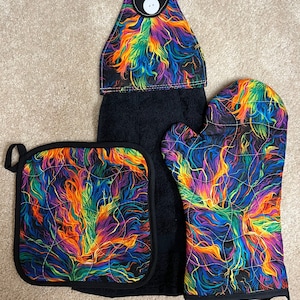 May include: A set of three kitchen towels with a colorful abstract design. The set includes a potholder, a tea towel, and an oven mitt. The design features a swirling pattern of blue, green, orange, and yellow.