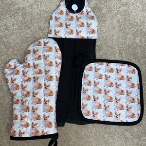 May include: A set of three kitchen accessories featuring a pattern of corgi dogs. The set includes a potholder, an oven mitt, and a dish towel.