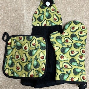 Può includere: Un set di tre asciugamani da cucina con stampa di avocado verde. Il set include un sottopentola, un asciugamano da cucina e un guanto da forno.
