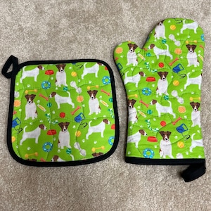 May include: A green oven mitt and a matching pot holder with a pattern of white and brown dogs, bones, and dog toys.
