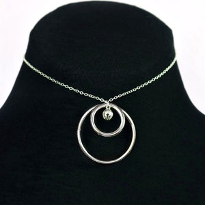 May include: A silver chain necklace with a double circle pendant and a small silver ball charm.