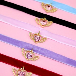 May include: Five velvet choker necklaces with gold winged heart pendants and pink rhinestones. The chokers are in the colours black, light pink, lavender, red, and light blue.