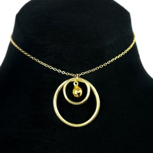 May include: A gold chain choker necklace with a pendant featuring two interlocking circles and a small bell charm.