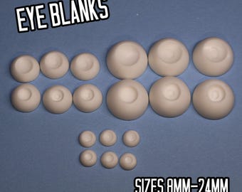 May include: A collection of off-white eye blanks in various sizes, arranged on a blue surface. The text "EYE BLANKS" and "SIZES 8MM-24MM" are displayed in white, outlined in black. The eye blanks range in size from small to large.