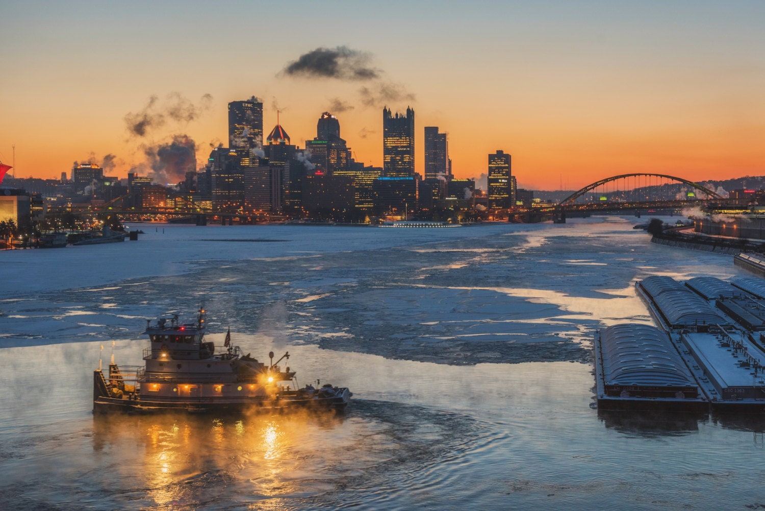 A loaded river barge under the West End bridge on the Ohio river with the  Rivers Casino and Heinz Field in the background in summer time, Pgh, PA, USA  Stock Photo 